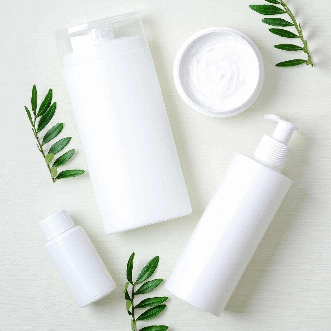 white bottles and container with green leafs